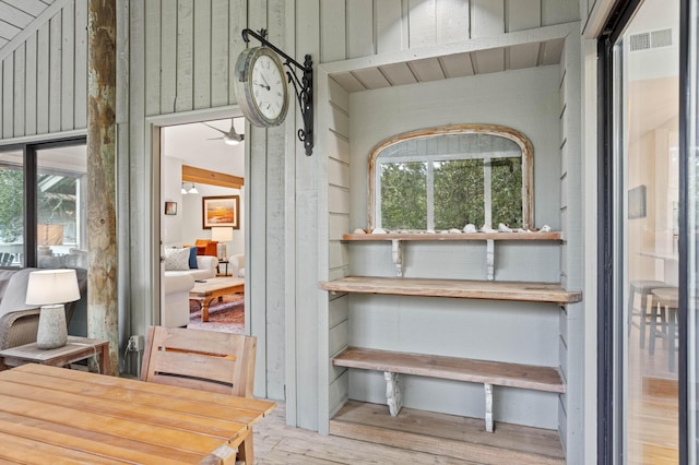 interior space featuring hardwood / wood-style floors, ceiling fan, and wooden walls