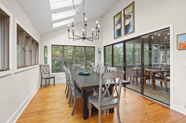 dining room featuring lofted ceiling with skylight, light hardwood / wood-style flooring, and a chandelier