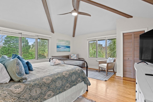 bedroom with ceiling fan, lofted ceiling with beams, light wood-type flooring, and a closet