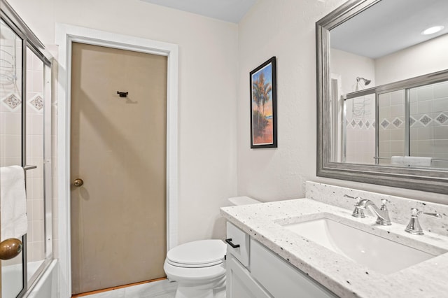 full bathroom with vanity, bath / shower combo with glass door, and toilet