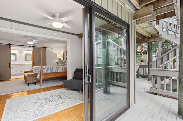 exterior space with wood walls, ceiling fan, a barn door, and light wood-type flooring