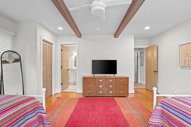 bedroom featuring ensuite bath, ceiling fan, beam ceiling, light hardwood / wood-style floors, and a closet