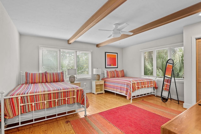 bedroom featuring ceiling fan, hardwood / wood-style floors, and beamed ceiling