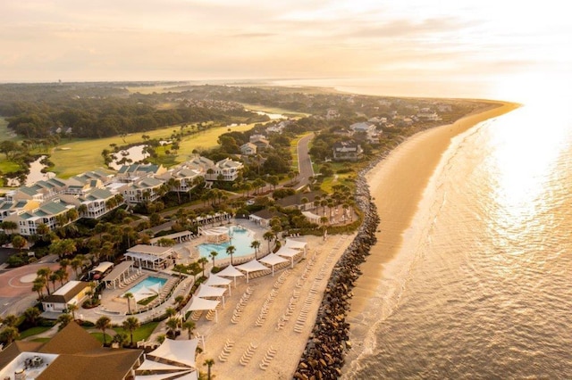 aerial view at dusk with a water view and a view of the beach