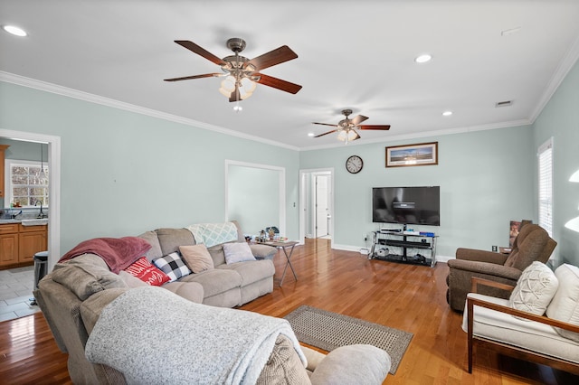 living room with visible vents, baseboards, light wood-style flooring, crown molding, and recessed lighting