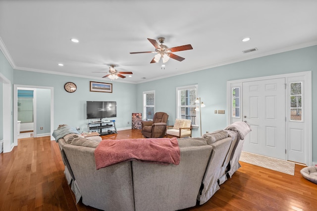 living area with ornamental molding, visible vents, and wood finished floors