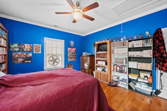 bedroom featuring attic access, visible vents, ceiling fan, wood finished floors, and crown molding