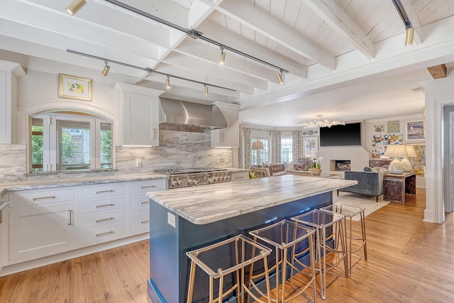 304 Bank St, Mount Pleasant, SC 29464 - kitchen featuring rail lighting, wall chimney range hood, a center island, white cabinets, and light wood finished floors