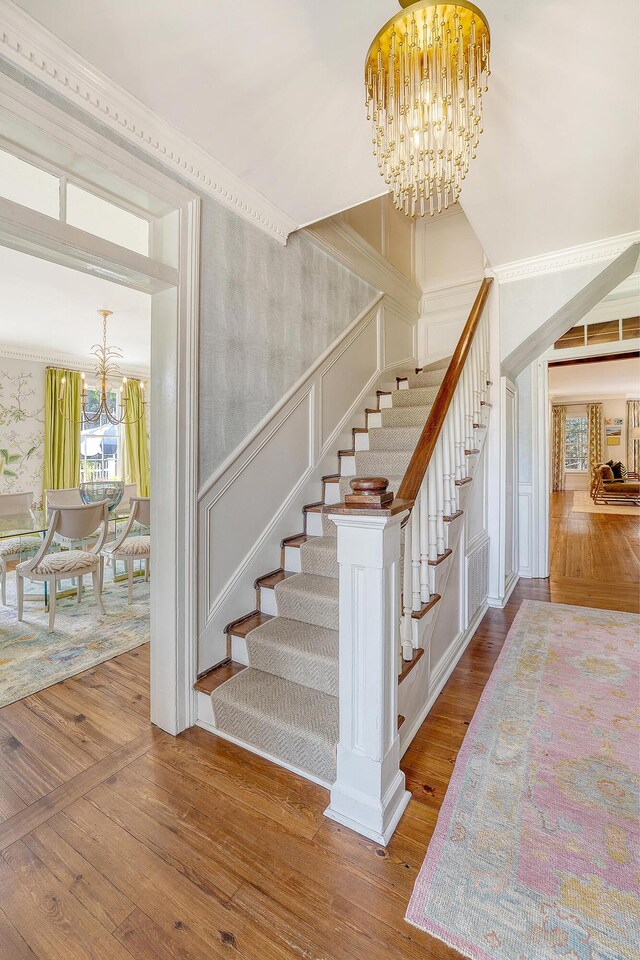 304 Bank St, Mount Pleasant, SC 29464 - staircase featuring a chandelier, wood-type flooring, wallpapered walls, a decorative wall, and a wainscoted wall