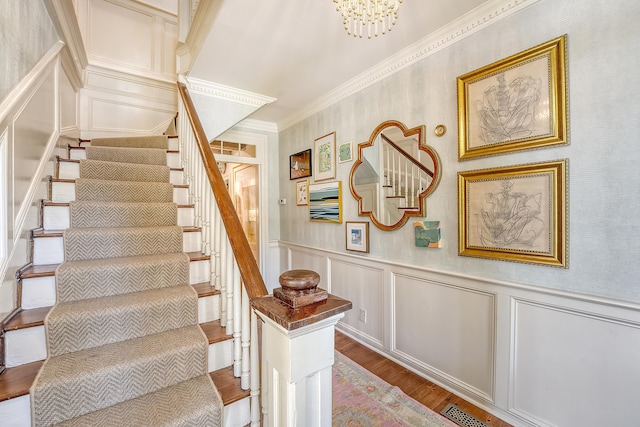 304 Bank St, Mount Pleasant, SC 29464 - staircase with a decorative wall, wood finished floors, crown molding, a wainscoted wall, and a chandelier