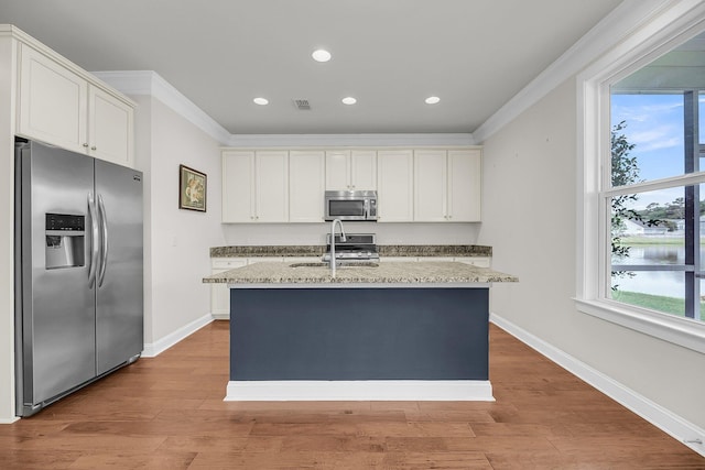3310 Hartwell St, Johns Island, SC 29455 - kitchen with appliances with stainless steel finishes, ornamental molding, light stone counters, a kitchen island with sink, and light wood-style flooring