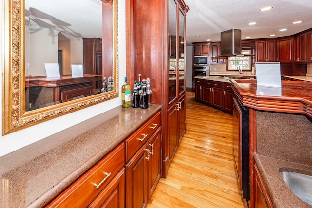 kitchen with a textured ceiling, light hardwood / wood-style flooring, stainless steel oven, and built in microwave