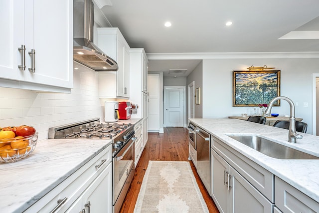 kitchen with light stone countertops, sink, wall chimney exhaust hood, stainless steel appliances, and white cabinets