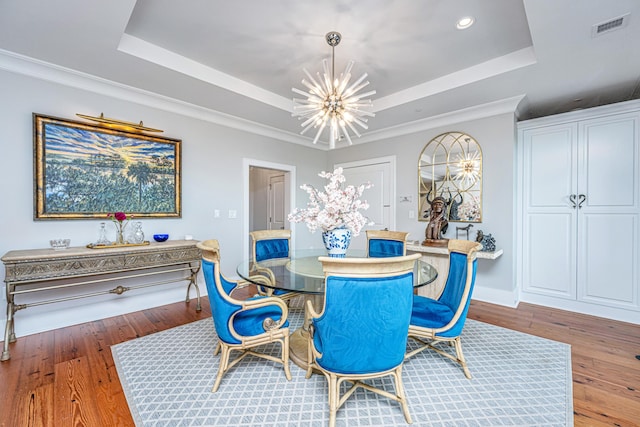 dining room with a tray ceiling, wood-type flooring, and an inviting chandelier