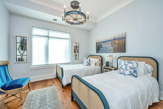 bedroom featuring a chandelier, light hardwood / wood-style floors, multiple windows, and crown molding