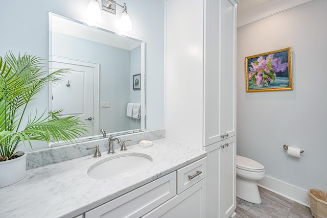 bathroom featuring toilet, vanity, and ornamental molding