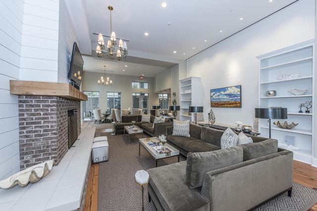 living room with an inviting chandelier, a high ceiling, and a brick fireplace