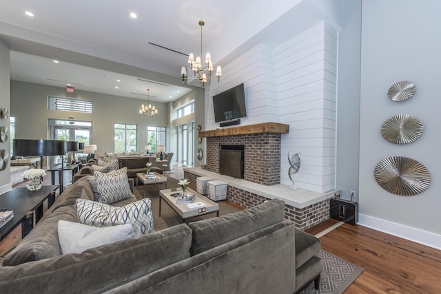 living room with hardwood / wood-style flooring, a chandelier, and a brick fireplace