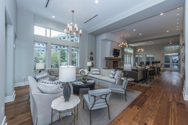 living room with a fireplace, a chandelier, and dark wood-type flooring