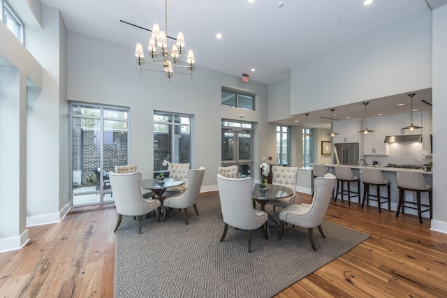 dining room featuring light hardwood / wood-style flooring, a towering ceiling, and a chandelier