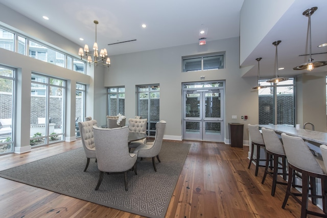 dining area with a chandelier, a towering ceiling, and dark hardwood / wood-style floors