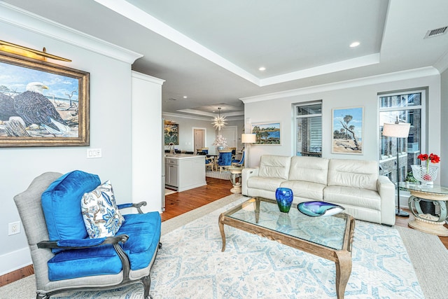 living room featuring a tray ceiling, crown molding, and hardwood / wood-style floors