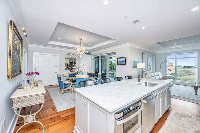 kitchen featuring light hardwood / wood-style floors, a raised ceiling, and a kitchen island with sink