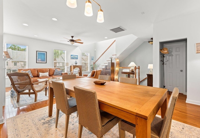 dining area with ceiling fan, light hardwood / wood-style floors, and a stone fireplace