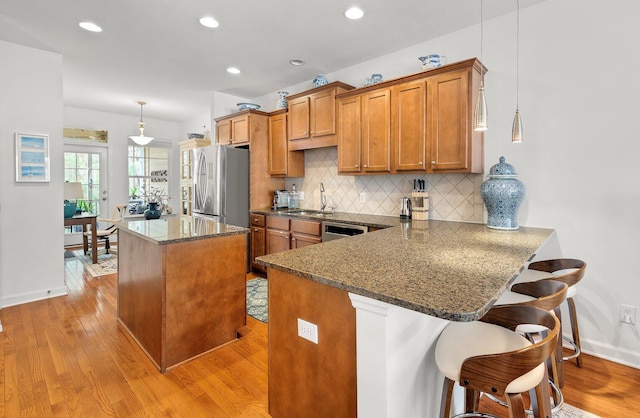 kitchen featuring decorative light fixtures, kitchen peninsula, sink, a kitchen breakfast bar, and stainless steel appliances