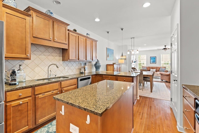 kitchen featuring a center island, dark stone counters, pendant lighting, stainless steel dishwasher, and sink