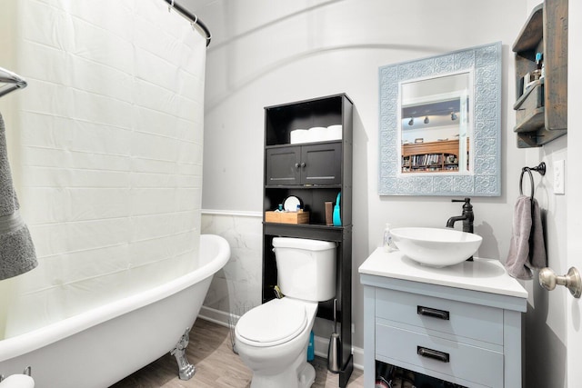 bathroom with toilet, hardwood / wood-style floors, a tub to relax in, tile walls, and vanity