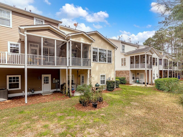 rear view of house featuring central AC unit, a sunroom, and a yard