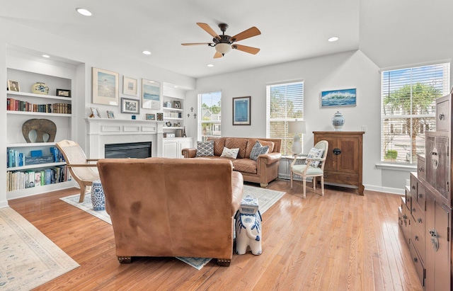 living room with ceiling fan, a healthy amount of sunlight, light wood-type flooring, and built in features