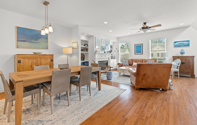 dining room with light wood-type flooring, ceiling fan, and built in shelves