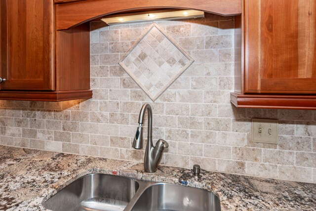 kitchen featuring decorative backsplash, sink, and stone countertops