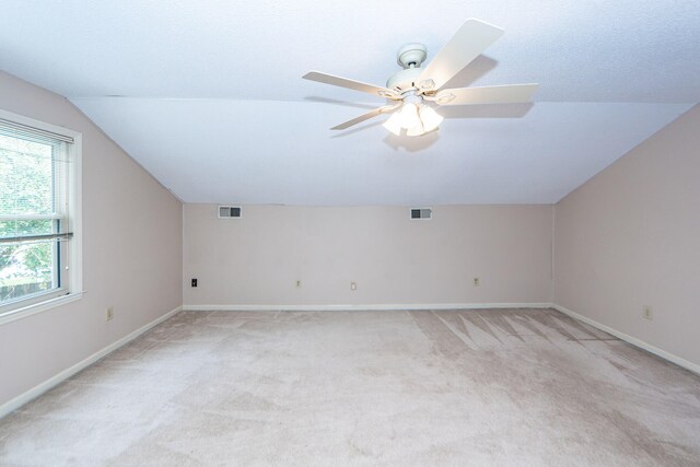 additional living space with vaulted ceiling, light colored carpet, and ceiling fan