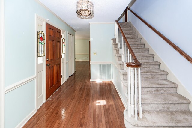 entryway with dark hardwood / wood-style floors and crown molding