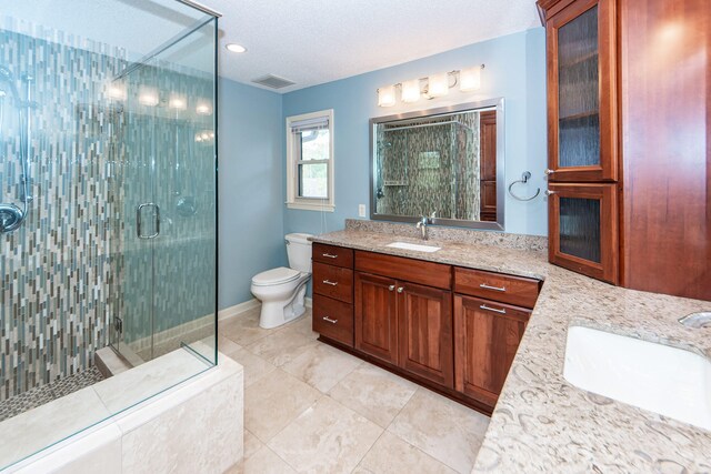 bathroom with vanity, a textured ceiling, toilet, and a shower with shower door