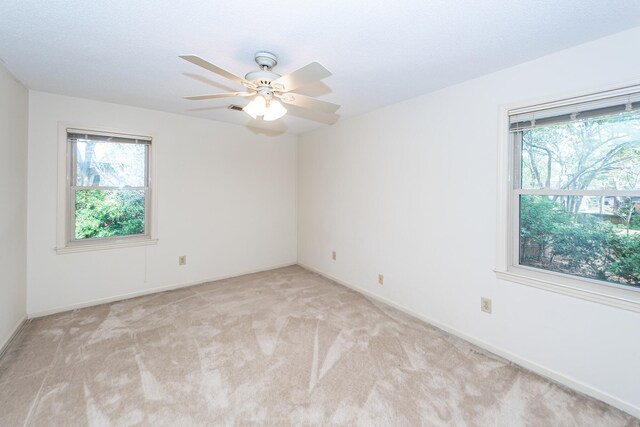 carpeted empty room with a wealth of natural light and ceiling fan