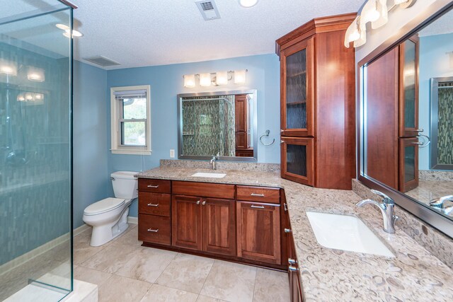 bathroom with walk in shower, vanity, a textured ceiling, and toilet