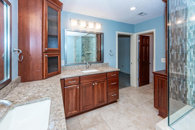 bathroom featuring vanity, a textured ceiling, tile patterned floors, and an enclosed shower