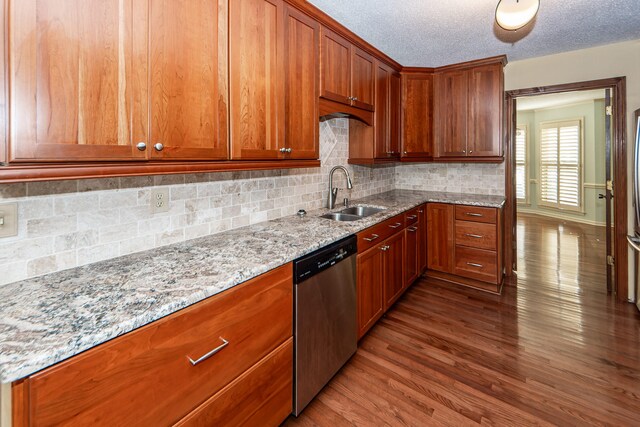 kitchen featuring dishwasher, hardwood / wood-style flooring, sink, backsplash, and light stone countertops