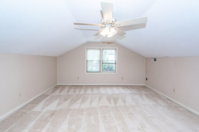 additional living space featuring lofted ceiling, a textured ceiling, light colored carpet, and ceiling fan