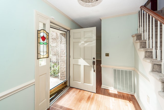 entrance foyer featuring ornamental molding, light wood-type flooring, and a textured ceiling