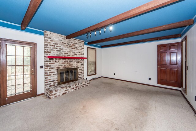 unfurnished living room with a fireplace, beamed ceiling, track lighting, and carpet floors