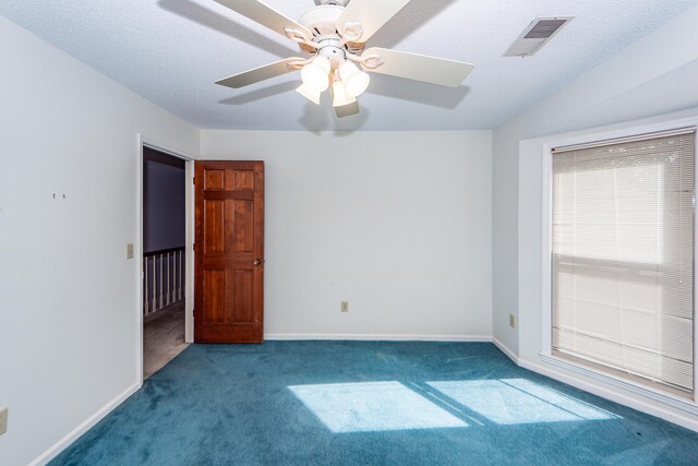 carpeted empty room with ceiling fan and a textured ceiling