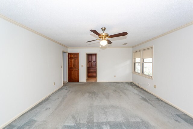 spare room featuring a textured ceiling, light carpet, ceiling fan, and crown molding