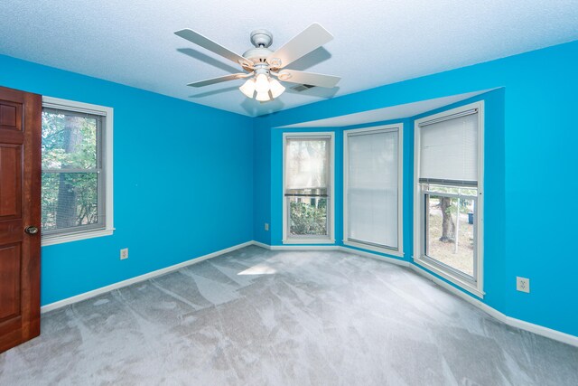 empty room featuring a textured ceiling, light carpet, and ceiling fan