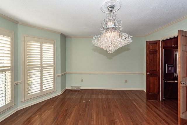 unfurnished room featuring dark hardwood / wood-style flooring, a textured ceiling, crown molding, and an inviting chandelier