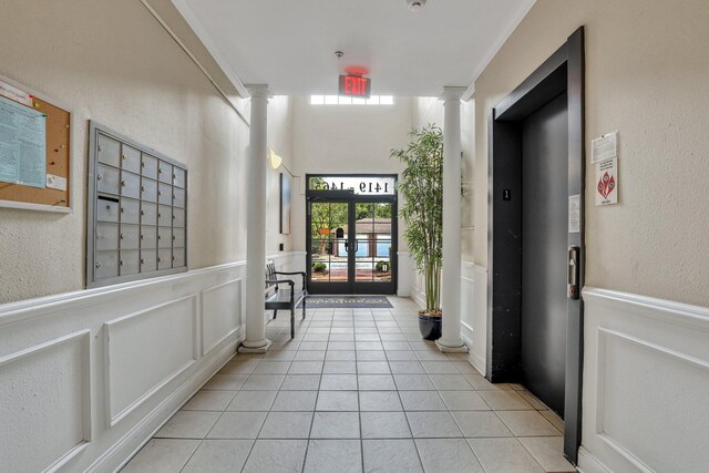 hall with elevator, light tile patterned floors, french doors, and ornate columns